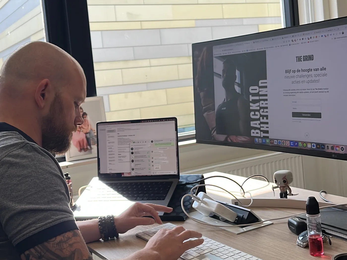 Een collega werkt achter twee schermen aan een website