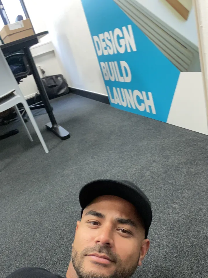 Een collega maakt een selfie voor de wandprint Design, Build, Launch