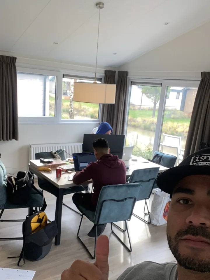 Een collega steekt zijn duim op, achter hem werken collega's door